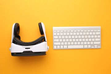 Virtual reality headset, keyboard and game controller on orange background — modern gaming and tech concept
