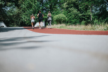 A group of three people jogging together on a paved track surrounded by lush greenery during daylight. Their activity emphasizes togetherness, health, and fitness in a serene outdoor environment.