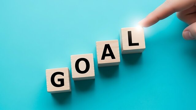 Finger touching glowing letter l on wooden blocks spelling goal against bright blue background for success concept - Powered by Adobe