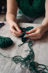 unrecognizable woman crocheting new item from green yard