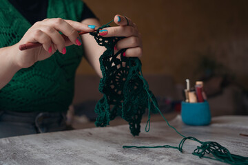 unrecognizable woman crocheting new item from green yard