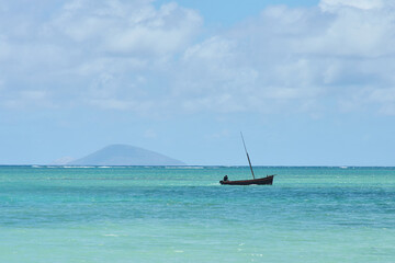 A scenic wooden boat cruises across clear tropical ocean waters, showcasing vibrant turquoise tones and a peaceful island atmosphere. The image captures a sense of adventure, freedom and paradise