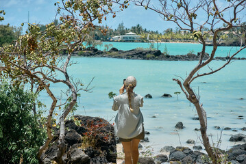 A beautiful woman enjoys spending time on the coastline with a scenic view of a tropical island in Mauritius. The image conveys relaxation, freedom, and a peaceful travel lifestyle