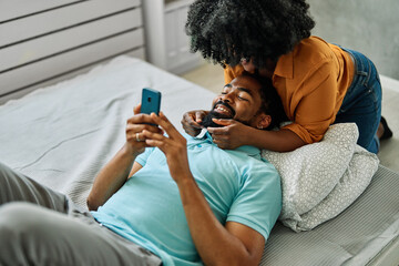 Portrait of a young happy couple having fun taking a selfie with camera on smartphone at home. Girlfriend and boyfriend bonding, love concept
