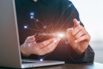 Connecting digital tools on a laptop while using a smartphone to manage data and tasks during office hours