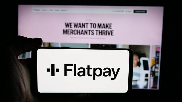 Stuttgart, Germany - 11-30-2025: Person holding cellphone with logo of Danish payment solutions company Flatpay ApS on screen in front of webpage. Focus on phone display.