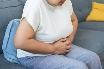 Sick asian senior woman in pain, hand holding belly, stomach pain from food poisoning, older hurt...