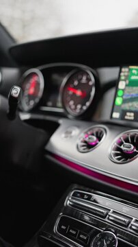 Car Dashboard With Illuminated Gauges, Ambient Purple Lighting And Touchscreen, Chrome Air Vents And Stitched Leather Trim, Center Console Buttons And Clock Visible, Modern Premium Cabin Mood