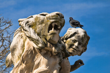 D&eacute;tail d'une statue d'un lion et d'un enfant sur la t&ecirc;te duquel se repose un pigeon.