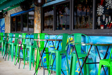 Tables with green chairs at a curbside restaurant