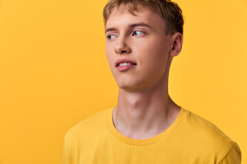 Close up of a young man in a yellow shirt against a bright yellow backdrop, a thoughtful expression and clean studio lighting, offering a modern, fashionable look for advertising, branding and