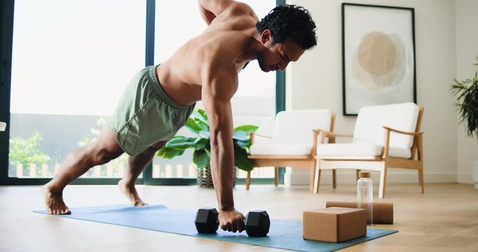 Man, fitness and weightlifting with dumbbells in home for exercise, muscle gain or training. Active, muscular or male person with equipment or weights for arm workout or renegade row on mat in house
