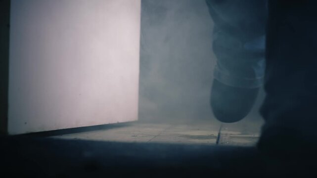 Person leaving dark smoke filled room through door