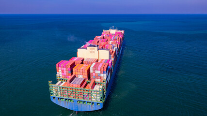 A container ship, fully loaded with goods, sails out to sea, delivering products to various locations around the world.