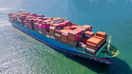 A container ship, fully loaded with goods, sails out to sea, delivering products to various locations around the world.