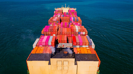 A container ship, fully loaded with goods, sails out to sea, delivering products to various locations around the world.