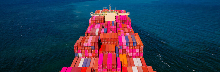 A container ship, fully loaded with goods, sails out to sea, delivering products to various locations around the world.