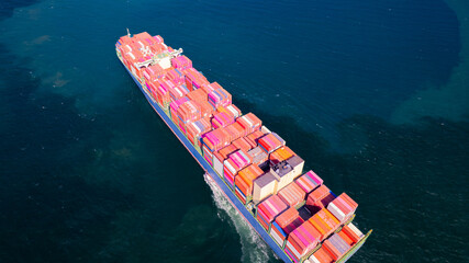 A container ship, fully loaded with goods, sails out to sea, delivering products to various locations around the world.