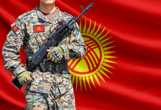 Kyrgyzstan flag with soldier in military uniform holding assault rifle in front of it