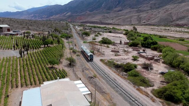 Vista a&eacute;rea con drone del Tren Solar atravesando vi&ntilde;edos en la Quebrada de Humahuaca, provincia de Jujuy, Argentina.