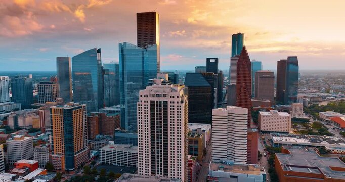 Gorgeous skyscrapers in the city downtown against colorful cloudy sky. Drone rising above panorama of Houston, Texas, USA at sunset.