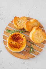Flamed Camembert with caramelized golden sugar crust and fresh rosemary on board