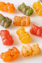 Colorful gummy bears with chili lime seasoning displayed on clean white plate