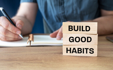 Symbol building good habits. Wooden blocks with a sign. Build good habits. Business concept. A person working at a desk in the background. Changing bad habits into good ones.
