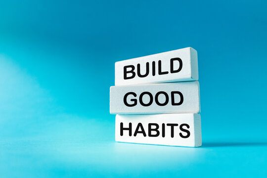 Symbol of building good. Wooden white blocks with text Build good habits. Beautiful blue background. Business concept. Copy space

. Close up