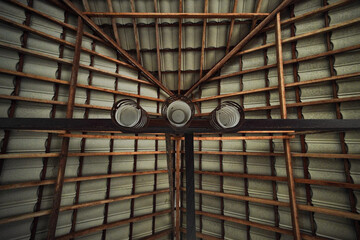 Unique perspective of a wooden ceiling with exposed beams and three modern pendant lights, creating a striking architectural detail