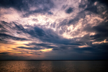 Obraz premium Dramatic sunset sky with dark storm clouds over the sea, moody atmosphere landscape