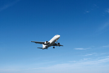 White Airplane Approaching for Landing Against Blue Sky and Clouds
