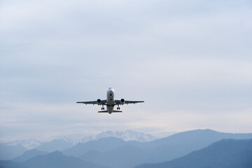 Airplane Climbing into Winter Sky Above Snowy Mountain Landscape. Powerful Takeoff of Commercial Airplane in Winter Mountain Setting