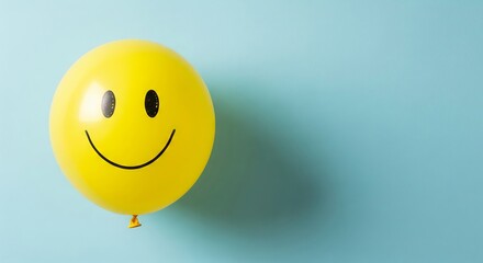 Yellow smiley face balloon on light blue background for cheerful party decor. concept of happiness, celebration, positive vibes