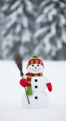 Fototapeta premium Happy snowman standing in a snowy winter landscape, wearing a red and green scarf, hat, and mittens, holding a small broom, for Christmas greeting card. copy space