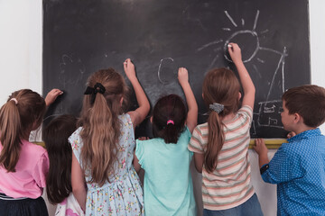 Children write and draw on the blackboard in elementary school while learning the basics of education