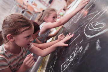 Children write and draw on the blackboard in elementary school while learning the basics of education