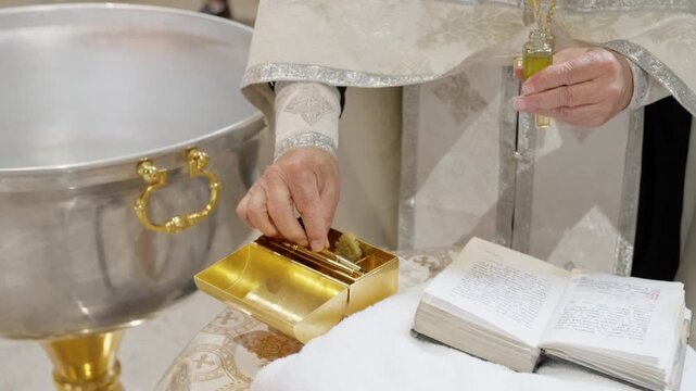 Sacred Ritual For Baptism Conducted, Religious Officiant Handles Vessel And Brush During Sacred Rite, Clergyman Meticulously Mixes Oil And Water To Conduct Baptismal Consecration Ceremony