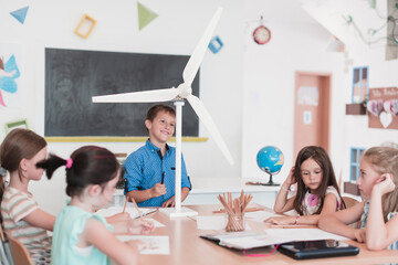 Fototapeta premium Elementary School Stem Robotics Classroom Diverse Group of Children Building and Programming windmill ecology robot concept. Together Talking and Working as a Team. Creative Robotics Engineering