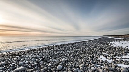 Snowy rocky beach at sunset with calm sea and serene sky