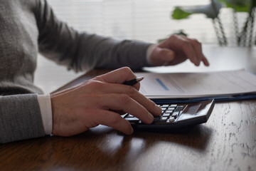 closeup of hand of business man using calculator, finance, businessman checking taxes and financial report in office