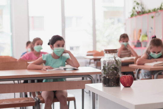 Multiracial group of kids wearing face masks working at class, writing and listening explanations of teacher in classroom - Powered by Adobe