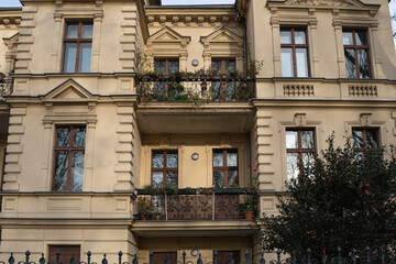 Elegant Building Facade with Intricate Balconies, Lush Green Plants, and Vintage Windows Creating a Charming Urban Scene