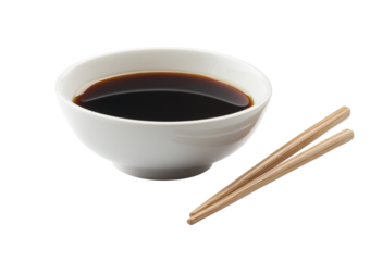 White ceramic bowl filled with dark soy sauce next to wooden chopsticks isolated on a transparent background