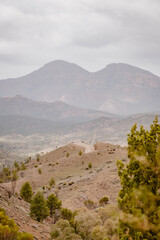 Vertical image of a mountain landscape with with sandy bare hills surrounded by desert greenery outdoor aon a foggy day in the Australian outback in Flinders Ranges in Australia with space for text.
