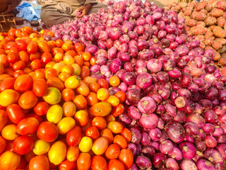 Fresh red tomatoes and onions piled at an outdoor market stall for healthy food and cooking ingredients