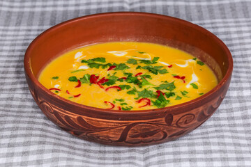 Pumpkin-lentil soup-puree with chili and greens in bowl