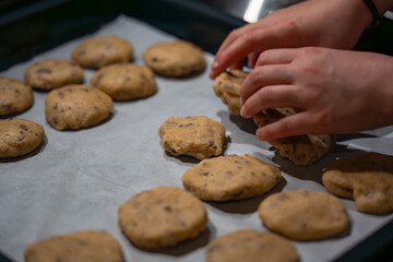 Kinderhände formen Plätzchenteig auf Backblech – hausgemachte Cookies in der Küche
Children's hands shape cookie dough on a baking sheet – homemade cookies in the kitchen