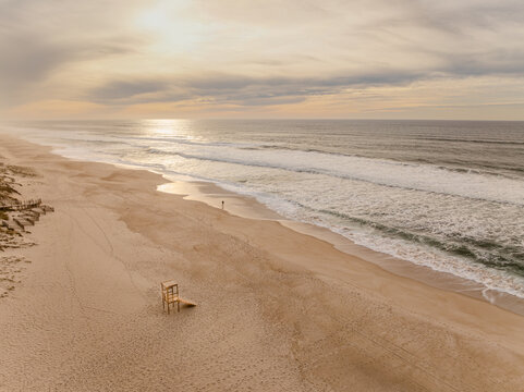 Aerial view of golden sands meeting the rhythmic ocean waves under a serene sky, lifeguard chair standing sentinel on the tranquil beach, Praia de Quiaios, Figueira da Foz, Portugal.