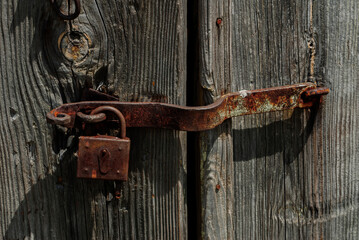 Old rusty metal padlock on a wooden door.